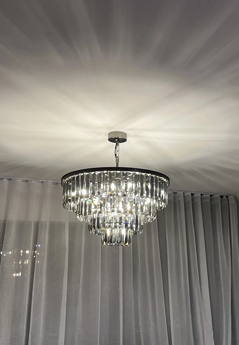 Tiered crystal chandelier lit up in a lounge