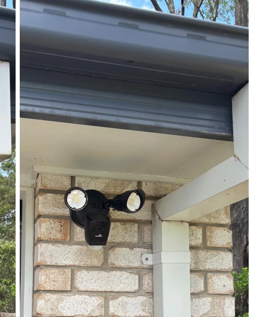 240V flood light camera mounted under the eave above a brick wall