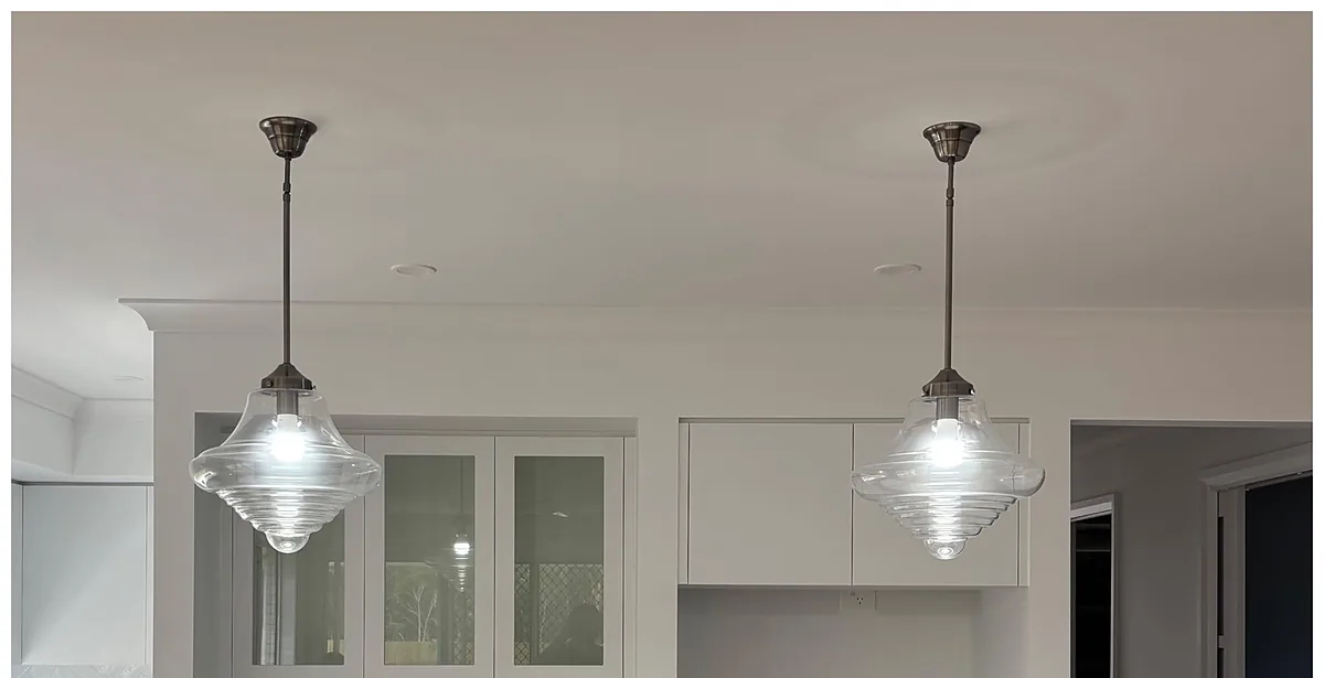 Pair of ribbed glass pendants hung over a white kitchen