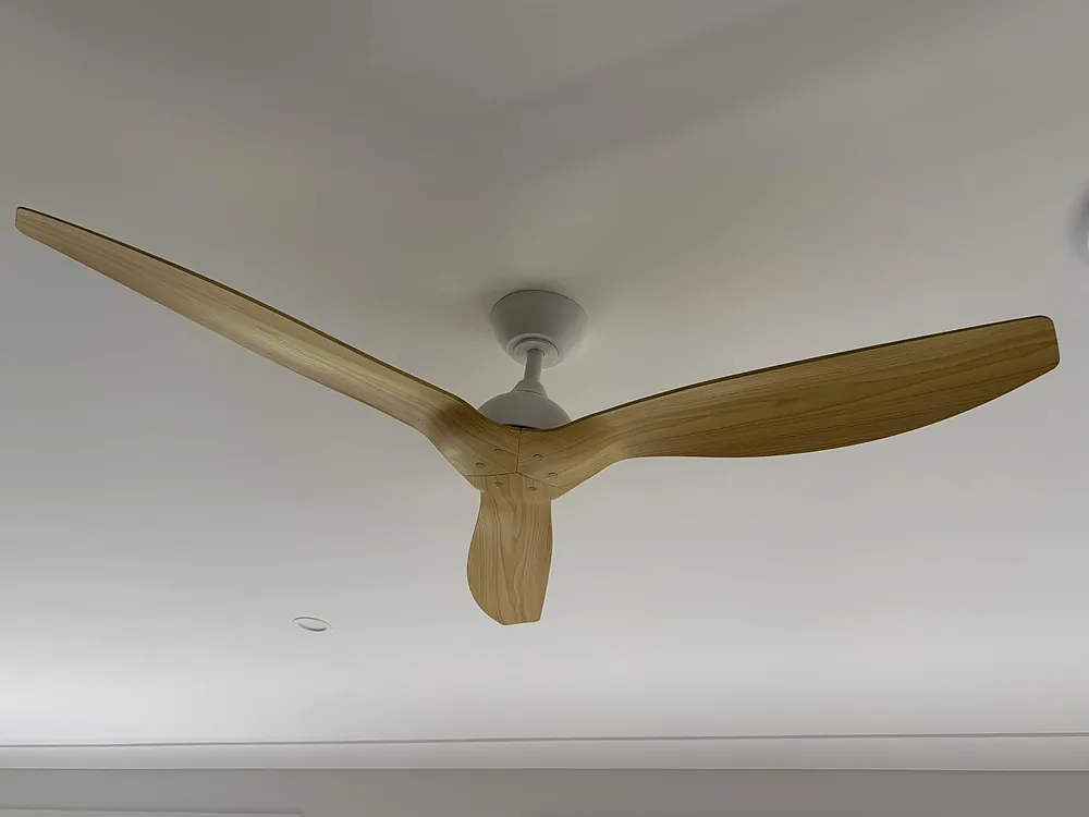 Three blade timber look ceiling fan installed in a white lounge ceiling