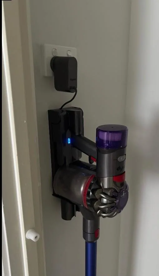 Cordless vacuum charging on a wall mount with a new power point inside a cupboard